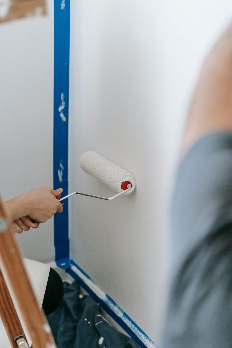 Handyman painting a wall white with a roller in North Naples.