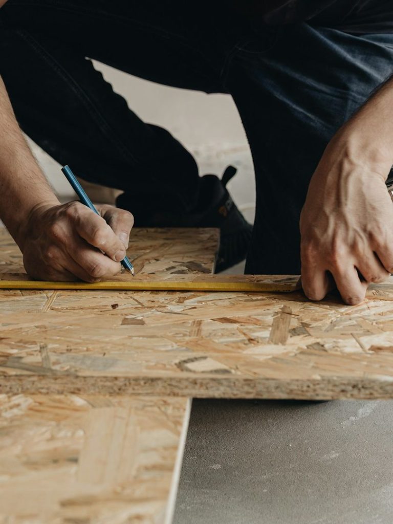 ZHR handyman measuring and marking a point on plywood.