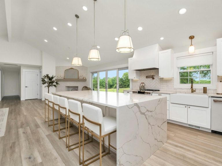 Modern kitchen with white cabinets, marble island, and pendant lights. Bright, spacious, and elegant. In Naples, FL.