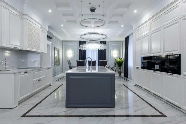Modern kitchen remodel with a central island, white cabinetry, and elegant lighting.