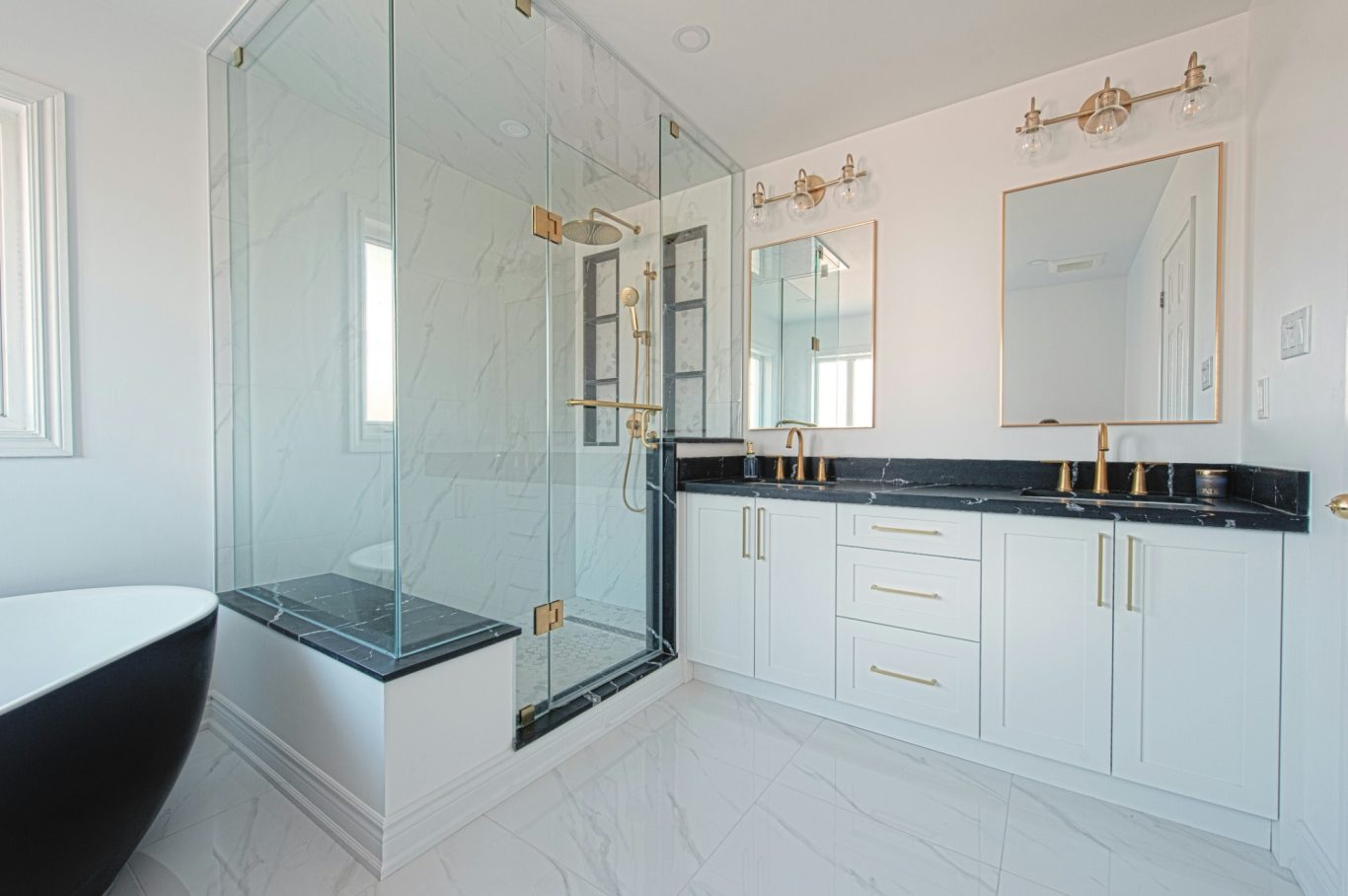 Modern bathroom remodel in North Naples with white cabinets, black marble counter top, and gold accents.