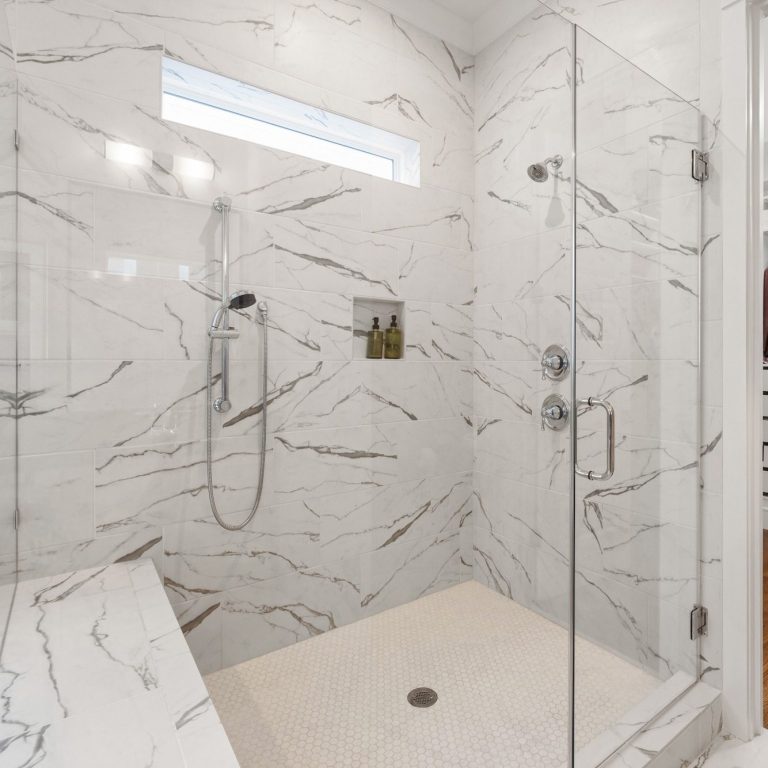 Modern shower with marble walls, glass enclosure, and a rainfall showerhead in North Naples.
