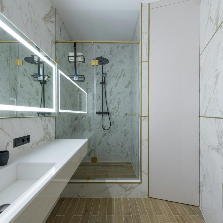 Modern bathroom remodel featuring a marble design, walk-in shower, and illuminated mirrors.