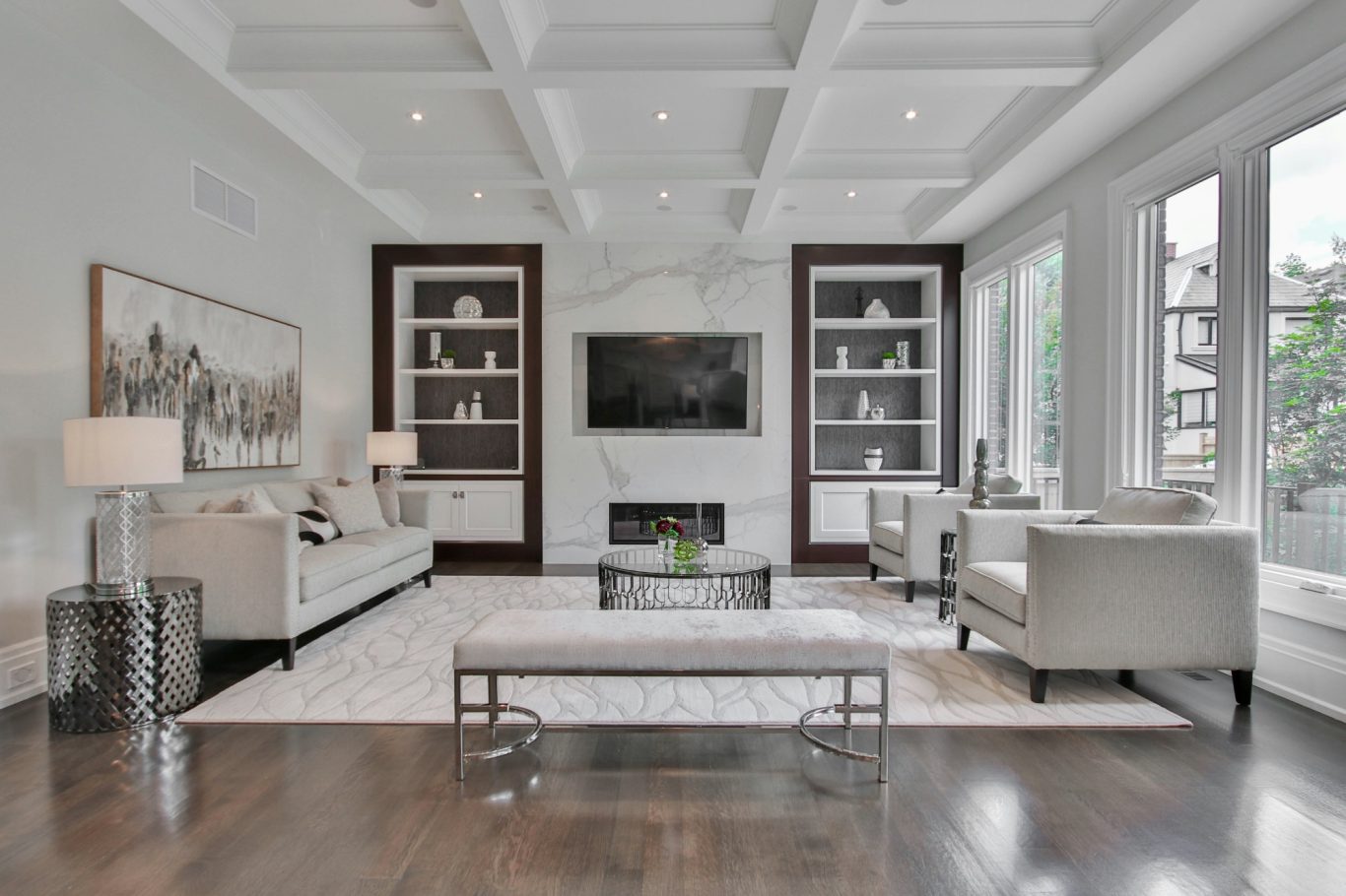 Modern living room with LVP flooring, white marble mantel, and white beams on the ceiling in North Naples.