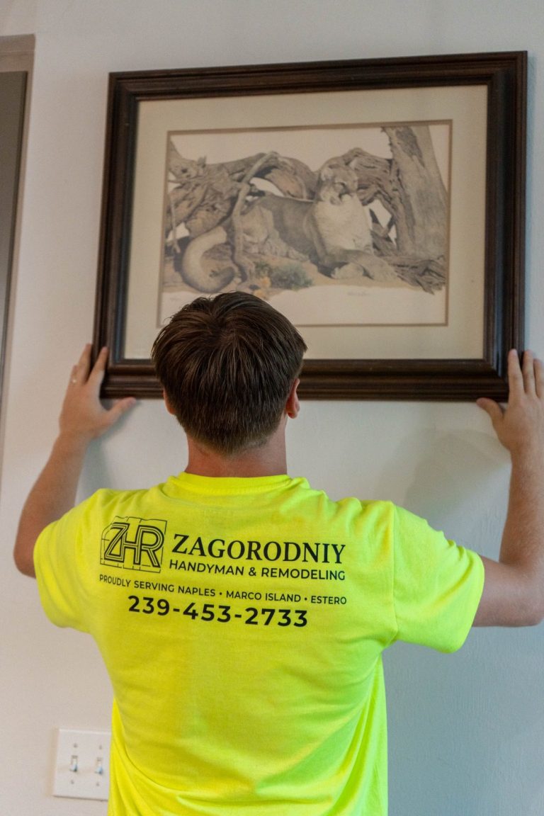 A handyman hanging a photo in a Naples apartment.