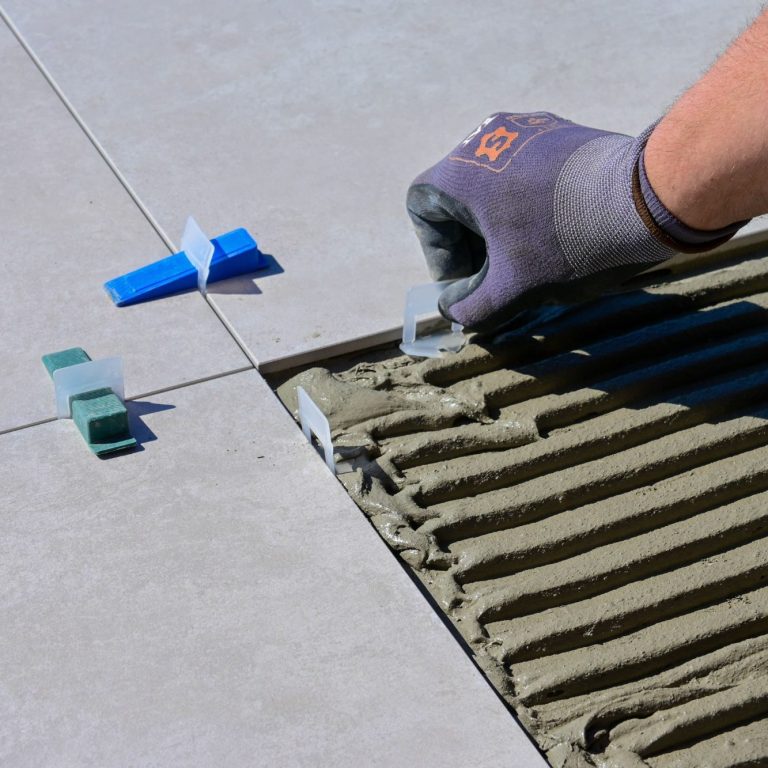 A handyman installing large, grey tile flooring in a Marco Island home.